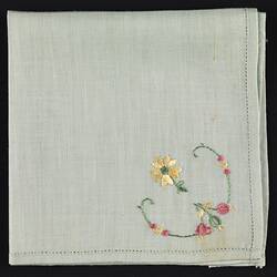 Folded green cotton handkerchief with embroidered flower.