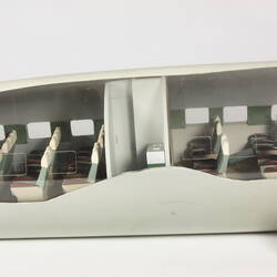 Model plane, front mid section. Cut-out side exposes miniature white, green interior and passenger seats.