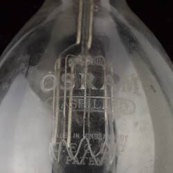 Detail of white text on clear glass globe with central filament.