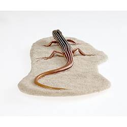 Cast model of brown lizard with bold white stripes.