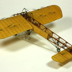 Model aeroplane with exposed wooden frame and off white panelling.