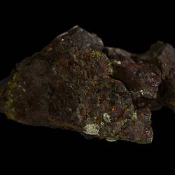 Brown rock with red, orange and green surface coating.