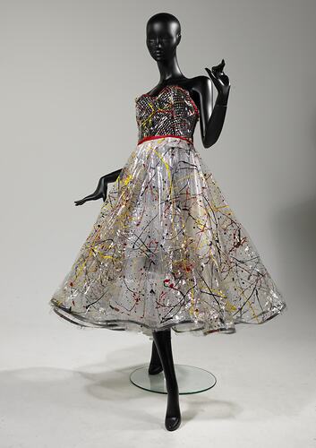 Dress with black bodice, clear plastic skirt covered with black, yellow, red paint splashes.