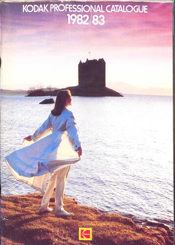 Cover page with a woman standing by some water, castle in background.