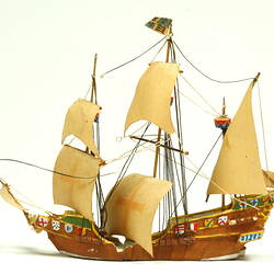 Side view of three masted ship with wooden hull.