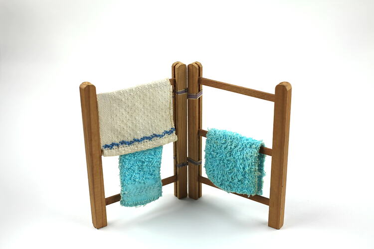 Upright wooden towel rack, with three towels.