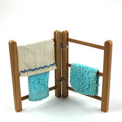 Upright wooden towel rack, with three towels.