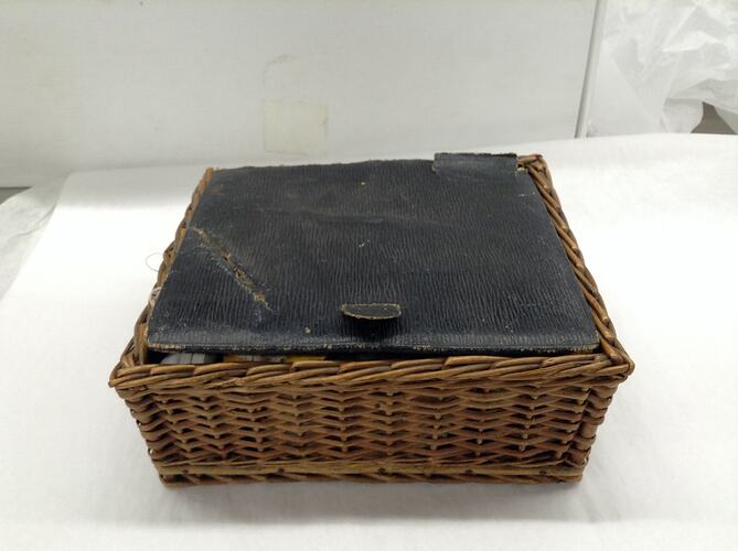 Woven cane sewing basket with leather lid.