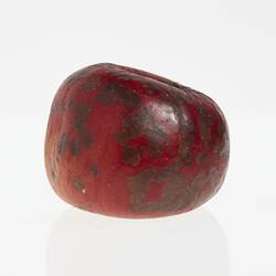 Wax model of an apple painted dark red. Has brown round spots.