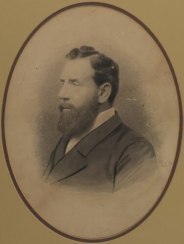 Three-quarter bust of man with dark beard and hair wearing white shirt and jacket.