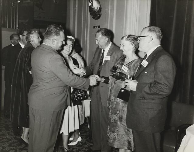 Men and women in formal dress at a Massey Harris Ferguson's event.
