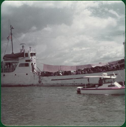 Over-loaded trawler 'Song Be 12' in harbour carrying Vietnamese refugees. Small boat in foreground.