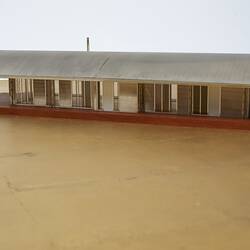 Model of a house with an arched roof, corrugated iron and wide expanses of glass.