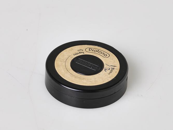 Round black case for spool of wire. Label affixed. Empty.