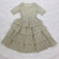 Short sleeve, round neck, cream dress with fine gold horizontal stripes. Four frilled layer skirt.