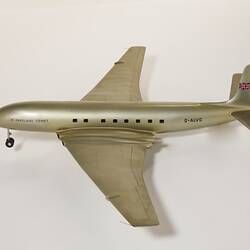 Silver model aeroplane, four wheels beneath each wing and two front wheels. British flag painted on tail.