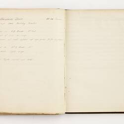 Open book with off white ruled pages. Handwritten text on left page.