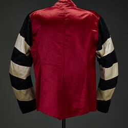 Back of red riding jacket with red buttons. Black and white hoops on sleeves. Short stand up red collar.