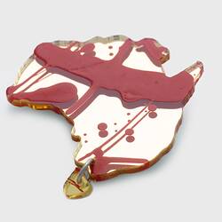 Gold acrylic sheet cut in the shape of Australia, with Tasmania attached via a single link. Splashes of red paint applied over base.