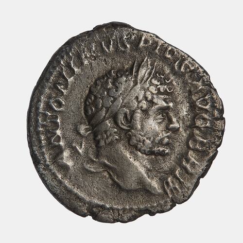 Roughly round silver coin. Bearded, wreathed man facing right. Text around.