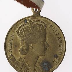 Round medal with profile of crowned woman, text surrounding.