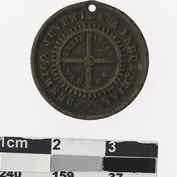 Round medal with wheel and text surrounding.