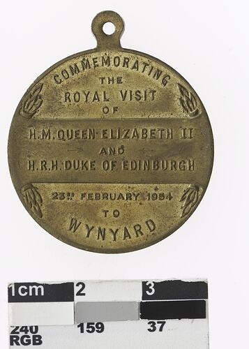 Round gold coloured medal with ten lines of text.