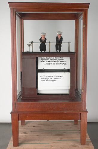 Mechanical amusement with little sailor men, in a glass case.