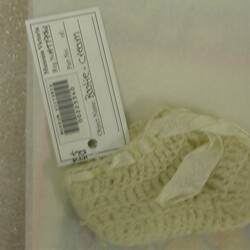 Cream woollen crocheted bootee, felted, with white rayon ribbon.