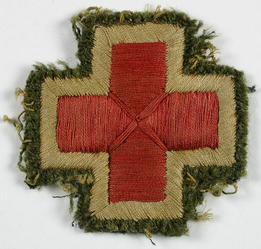 Red cross embroidered patch in red thread with a light-khaki green and dark green boarder.