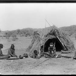 Arrernte family with possessions in front of a bough shelter, Alice Springs, Central Australia, 1896