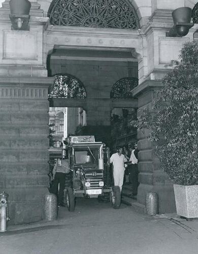 A tractor in the portico entrance to a building.