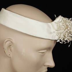 White headdress with beads grouped together at front.