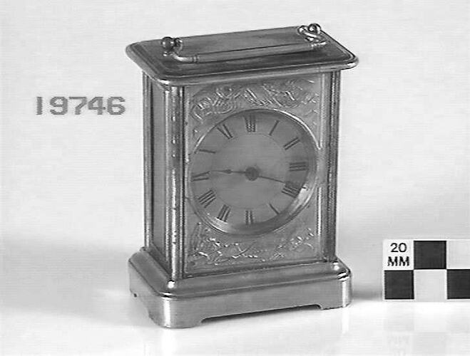Metal carriage clock with decorative front.