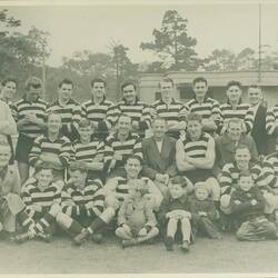 Football team and others posed outside clubrooms.