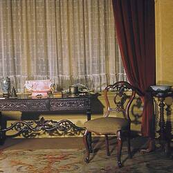Room interior with ornate furnishings including a carved side table.