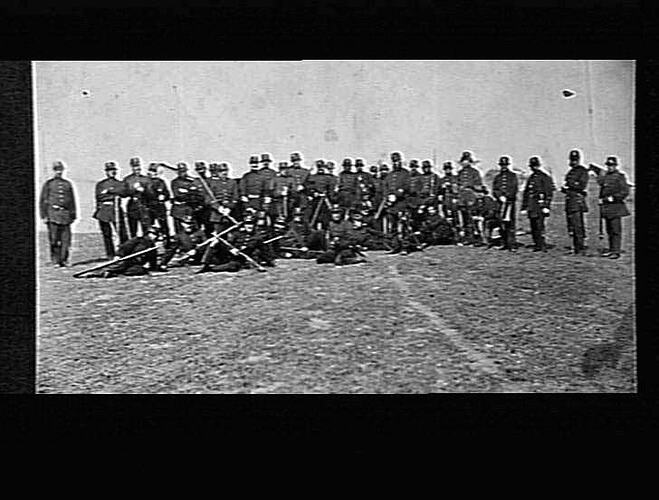 Group of uniformed men in field.