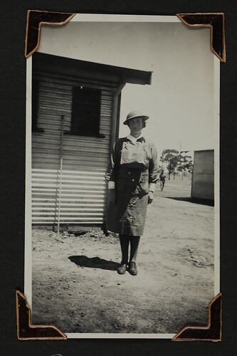 Woman in uniform standing in front of a shed.