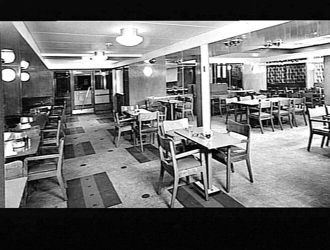 Ship interior. Cafe area with chequered metal chairs around tables.