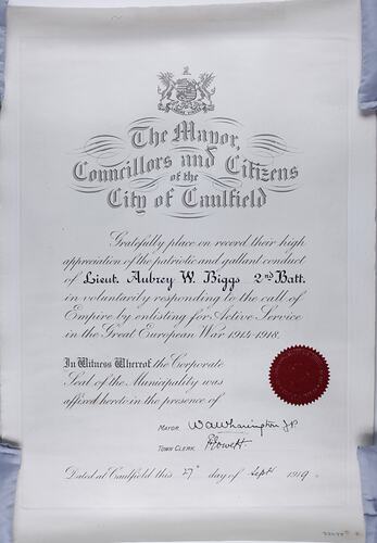 Certificate with written text, red stamp seal at bottom right hand corner and coat of arms top centre.