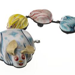 Wind-up metal white & blue rabbit towing three smaller yellow, pink then blue rabbits.