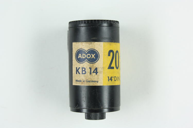 Cylindrical black plastic cartridge with printed paper label.
