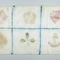 Back of rectangular cloth crudely marked into six squares containing shapes