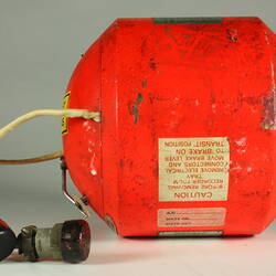 Red cylindrical container with two electrical cords at one end.