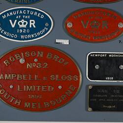 Five oval and rectangular plates in blue, red and black. All have raised lettering.