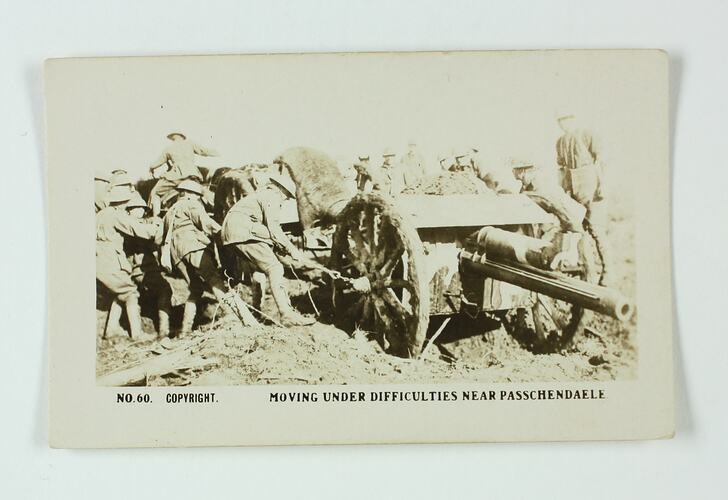 Group of servicemen pulling artillery gun with chains.