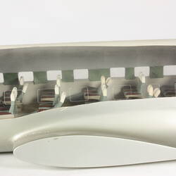 Model plane, mid section. Cut-out side exposes white, green interior and passenger seats. No wing.