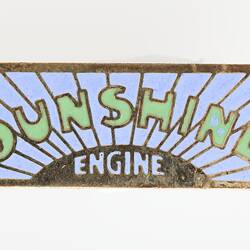 Rectangular pale blue with radiating lines from sun featuring word 'ENGINE' at base. Above 'SUNSHINE' text in