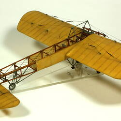 Model aeroplane with exposed wooden frame and off white panelling. Side view.