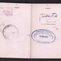 Open passport with two white pages with printed pattern. Printed and handwritten text. Mulitple stamps.